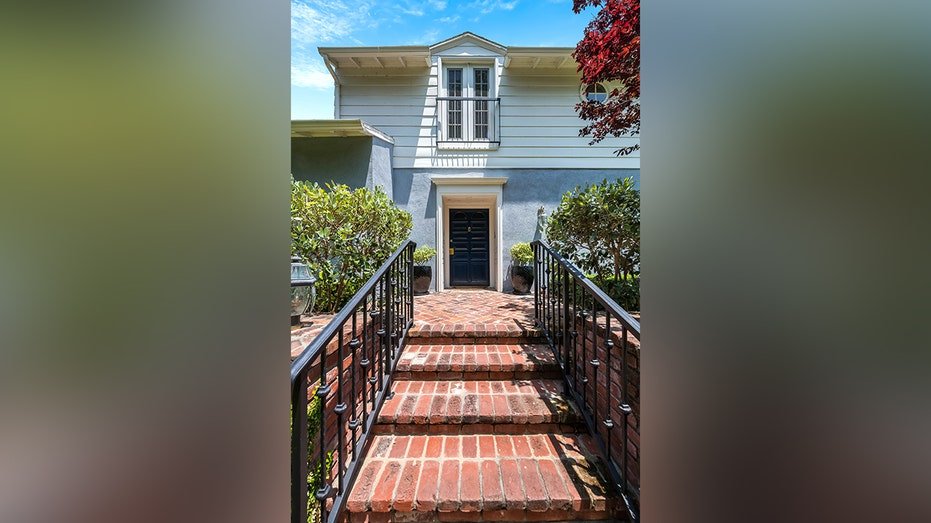 A group of brick stairs leads to the front door of the blue and white house.