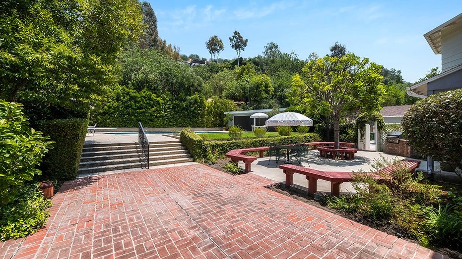 The backyard is characterized by a courtyard with red seats and brick area.