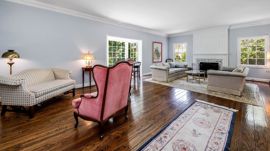 The living room has blue walls, a fireplace located on firewood and a door that leads to the backyard.