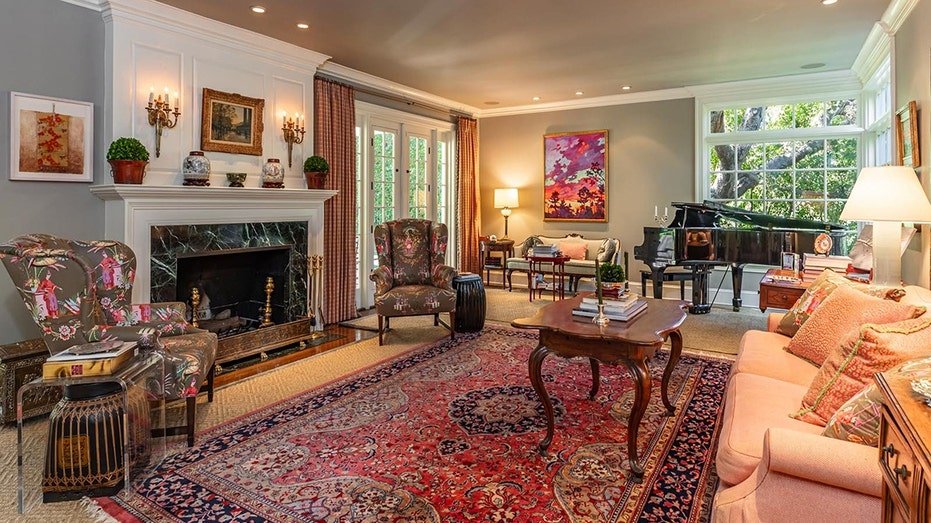 The living room includes a fireplace on firewood as well as multiple windows that bring natural light.
