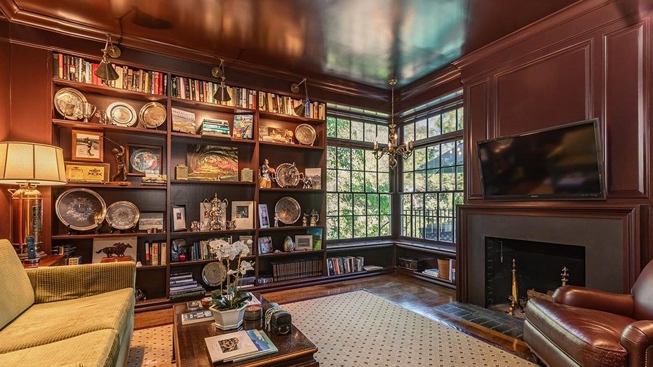 The library features a fireplace located on firewood as well as books shelves from floor to ceiling.