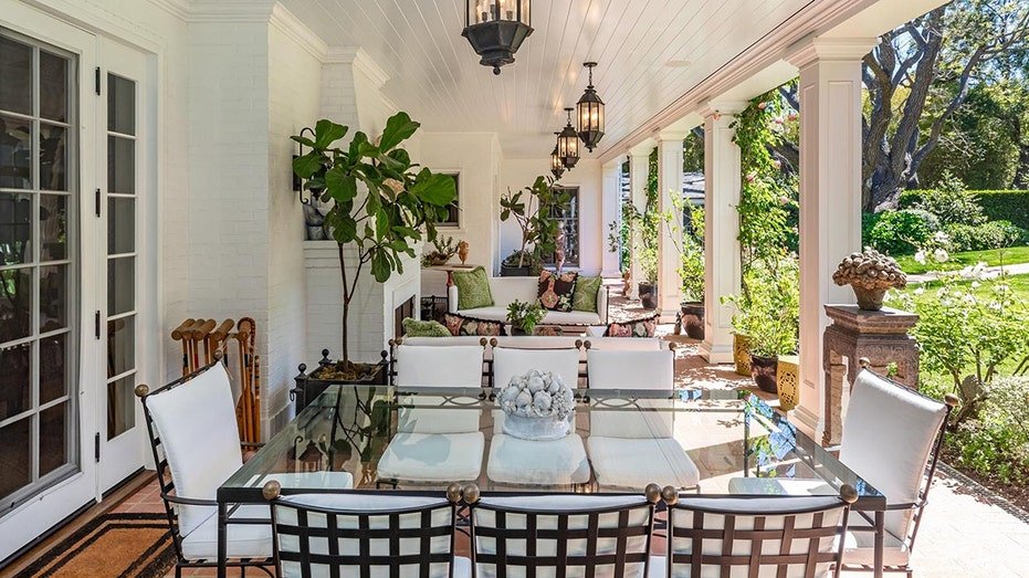 The covered front balcony is characterized by an external seating area and a dining area with an outdoor fireplace.