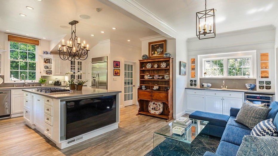 The kitchen includes a large central island with white cabinets and gray surfaces.