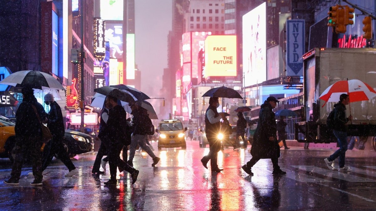 People cross the street at night during rain