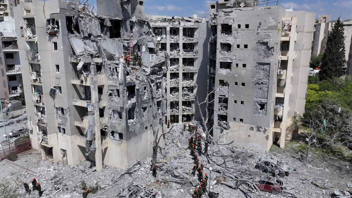 Israeli rescue workers are searching for the rubble and twisted debris outside a residential building collapsed in a modern air strike.