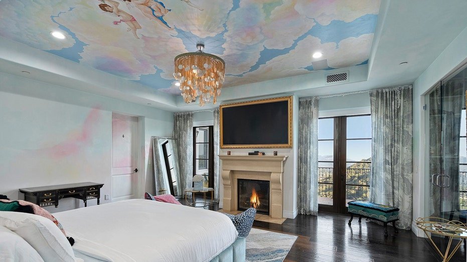 The primary bedroom features a wood burning fireplace and a plated ceiling to look like a sky.