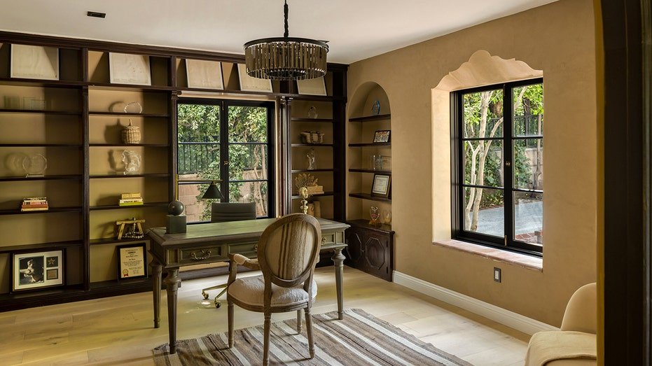 The office includes integrated shelves and multiple windows.