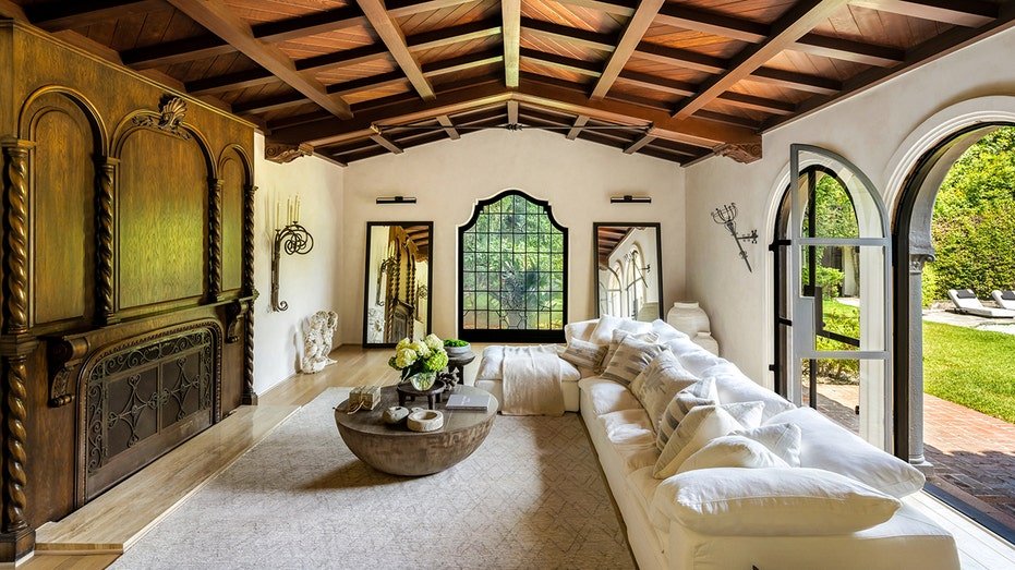 The living room features a fireplace of wood and ceilings covered with large arched doors and doors leading to the backyard.