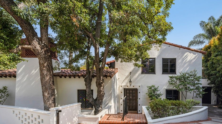 The house features long trees and a brick corridor leads to the front door.