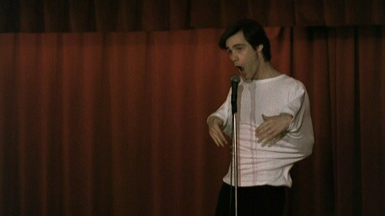 Jim Carrey leads to the stage against a red curtain in Pink Cadillac