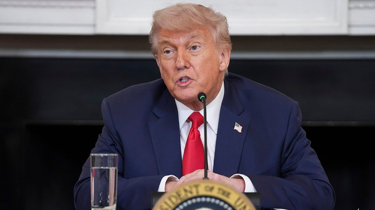 President Donald Trump wears a red tie, sitting while he was talking