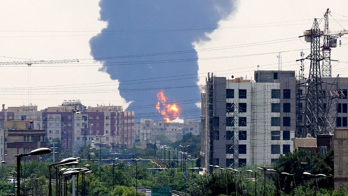 A huge column of smoke and fire rises from a distance in southern Tehran