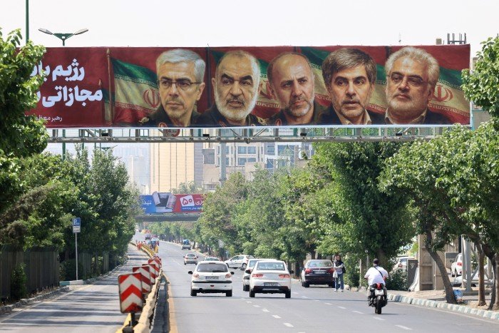 A poster displays pictures of Iranian military generals and nuclear scientists who were killed in the Israeli attack hanging on a bridge in Tehran