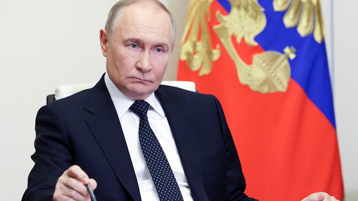 Russian President Vladimir Putin carries the pen on the table