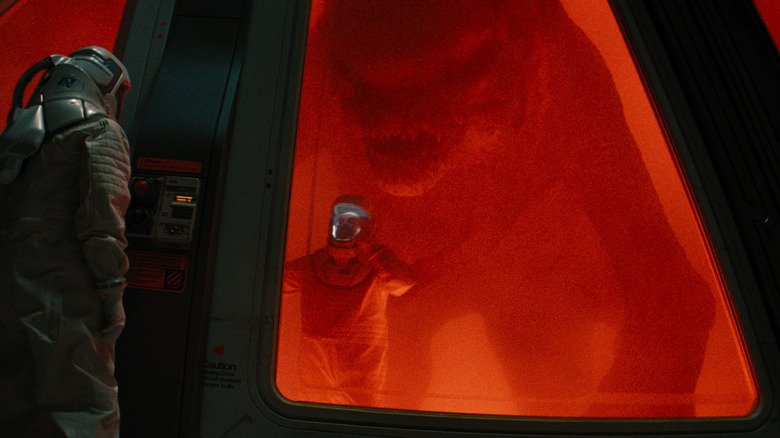 D-REX Silhoutged with red lights sneaks behind a world at the door of an explosion in a new new birth
