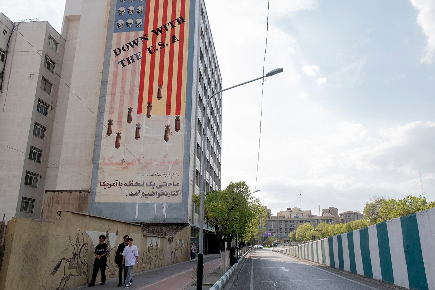A mural reads "Lower with the United States" With bombs falling from the stripes in the American flag.