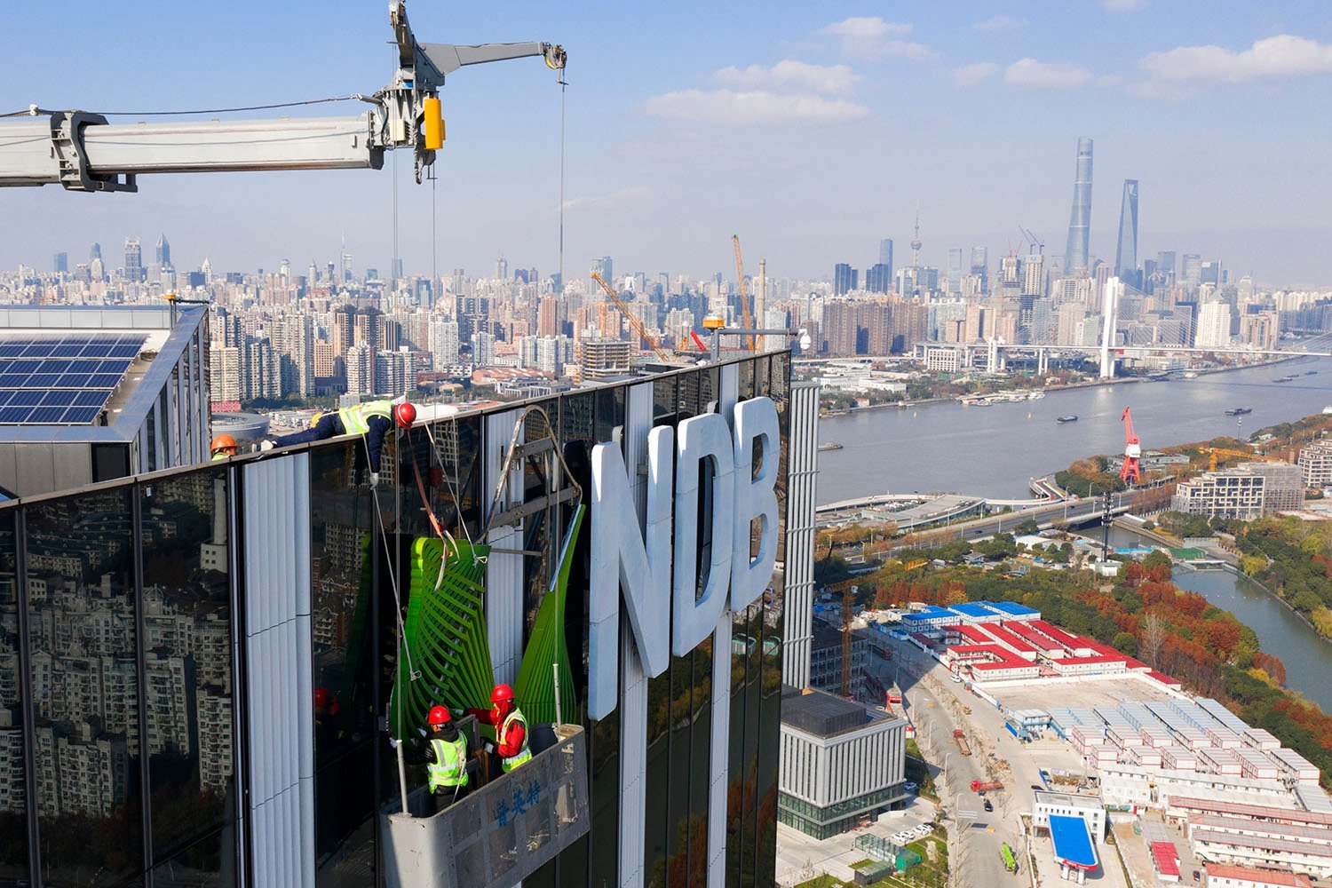 Building workers install the new Development Bank logo in Shanghai.