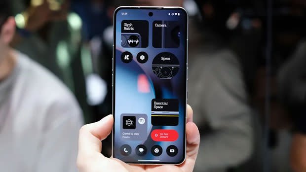 A picture of nothing on the phone 3 held in his hand in front of the background of his dark peach for a crowd of people.