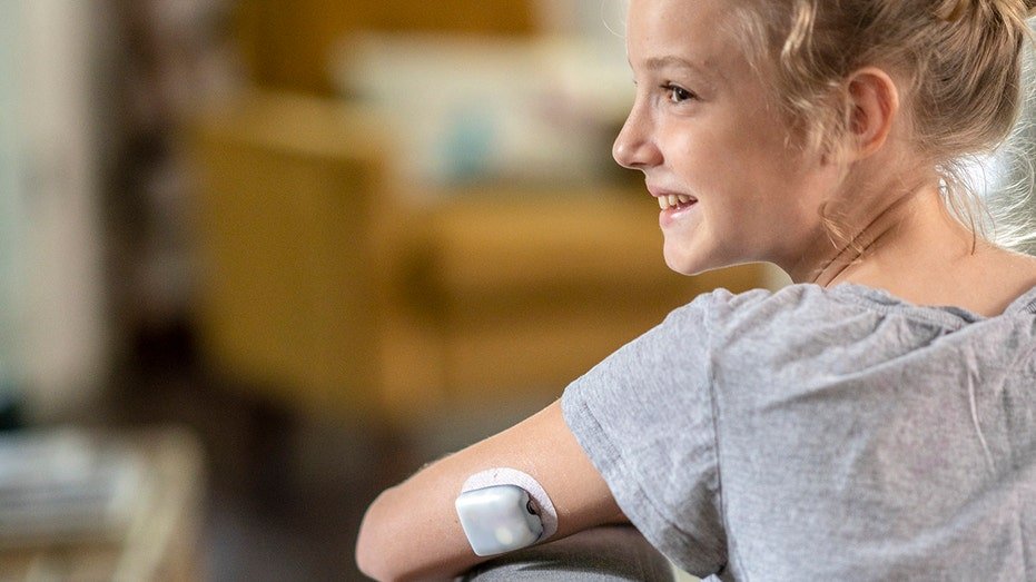 Diabetes girl sits on the sofa with CGM on her arm