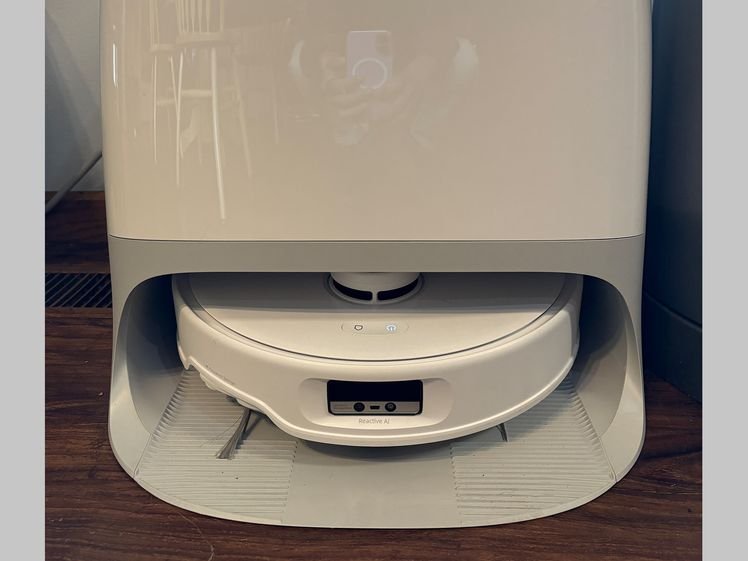 White rectangular device with rounded edges and a disc-shaped robot vacuum docked at the base