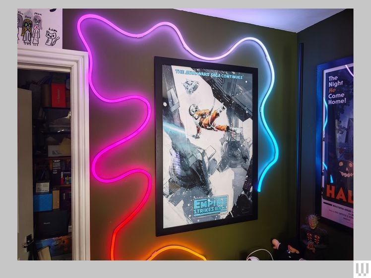 Wavy tube of neon lights attached to a wall, swirling around a poster