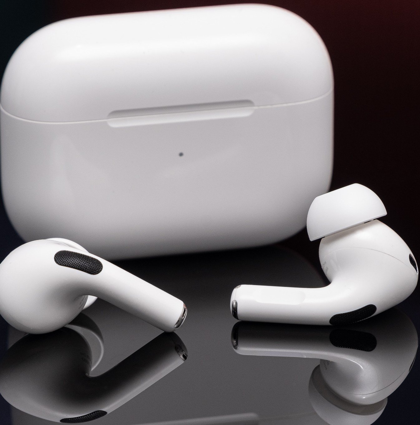AirPods of the second generation of Apple was photographed on a reflective black surface.