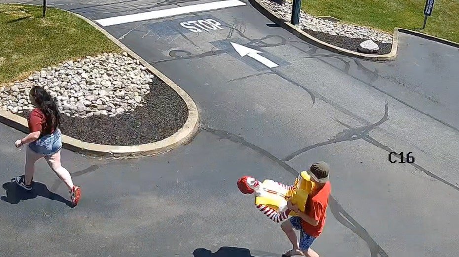 An individual holds the statue of Ronald McDonald