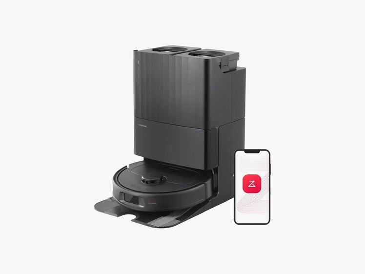 Roborock Qrevo S, a black disc-shaped robot vacuum at the base of a rectangular dock with a mobile phone beside it