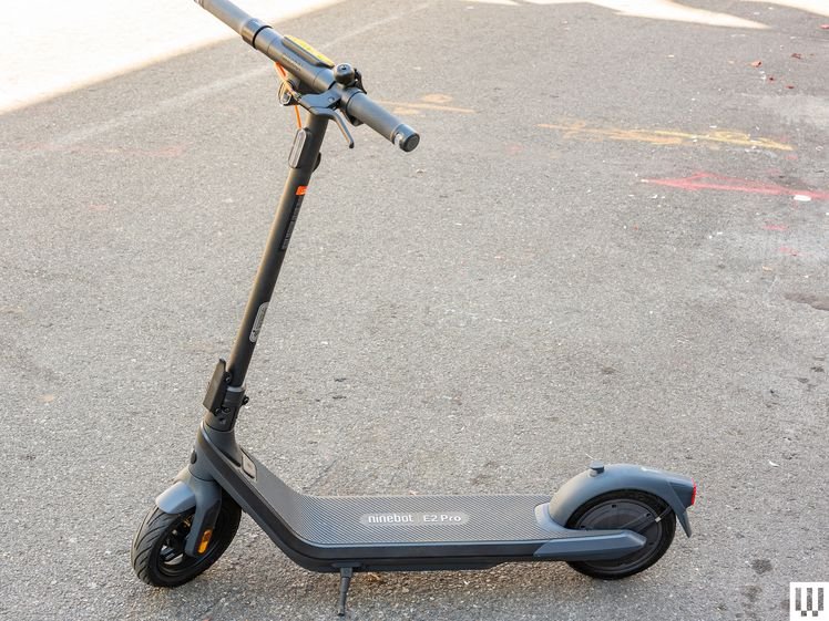 Side view of a Segway E2 Pro, a black electric scooter, parked on concrete
