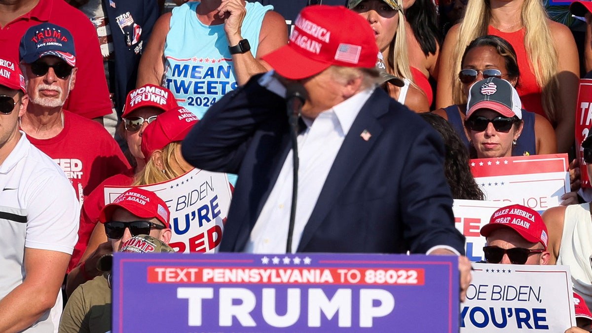 Donald Trump interacts with multiple shots during a campaign gathering
