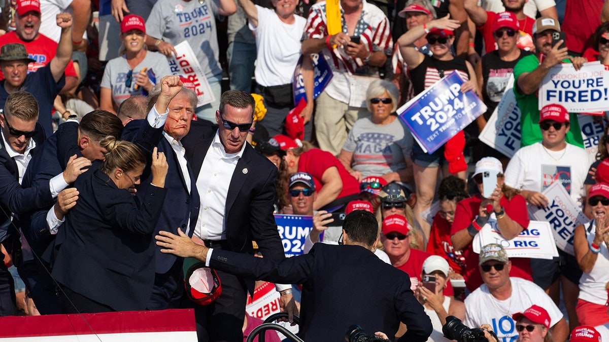 Donald Trump appears with blood on his face surrounded by secret service