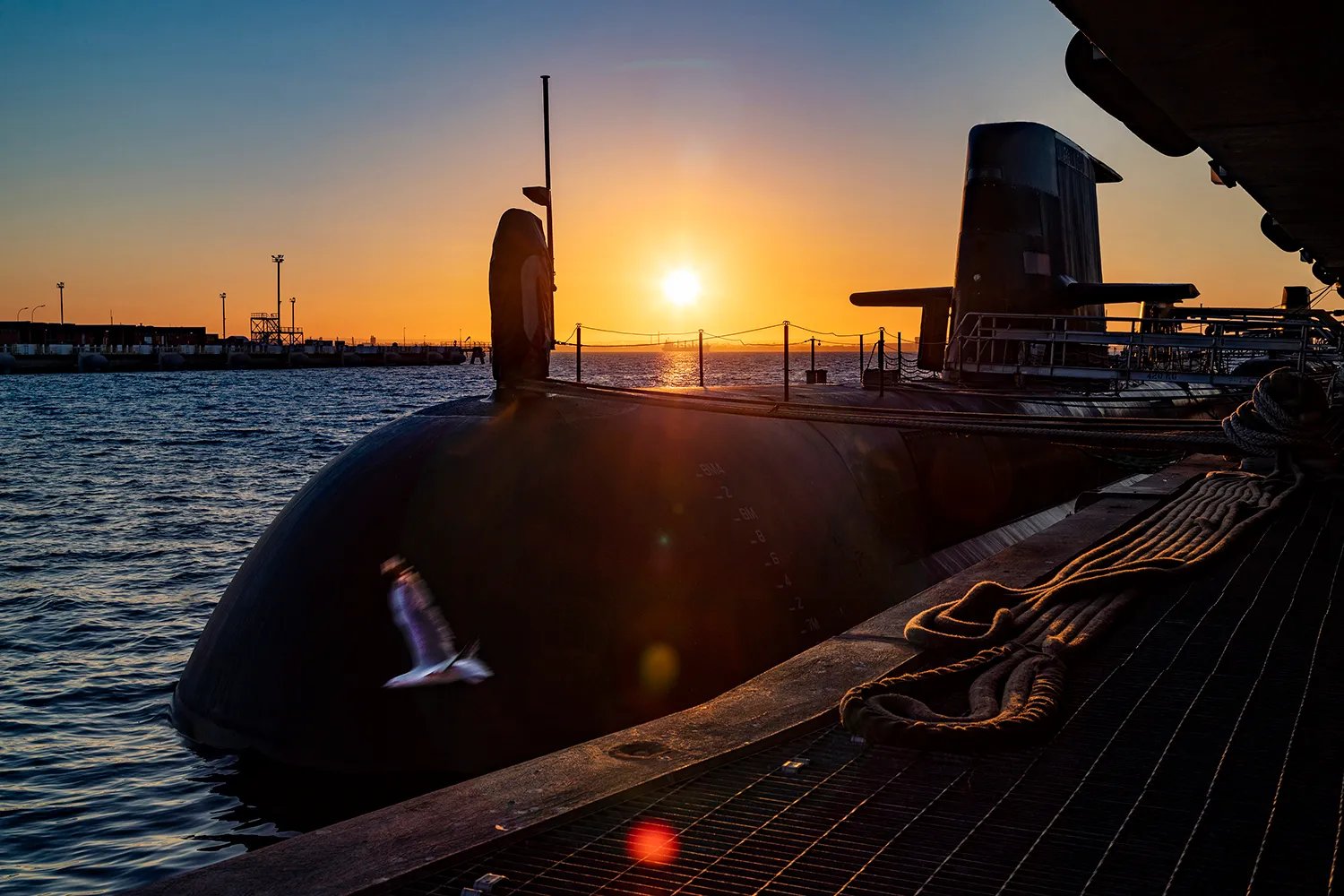 A submarine is pictured at a dock as the sun rises.