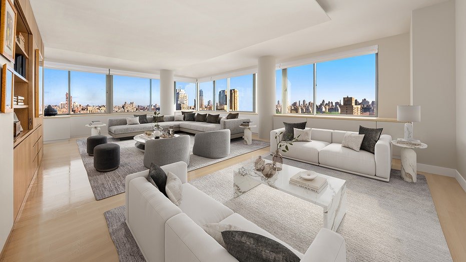 The living room features windows from floor to ceiling with views of the city.