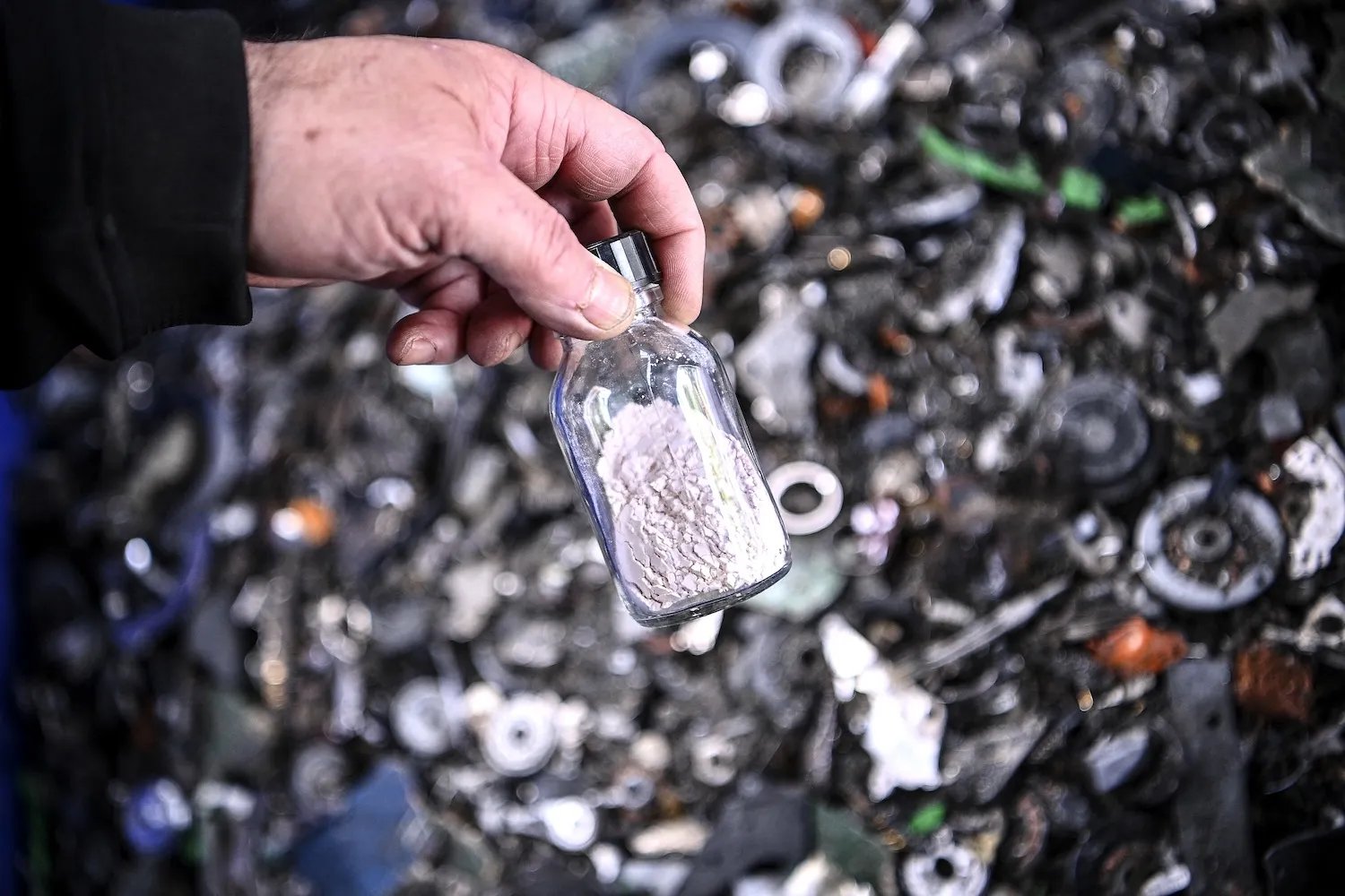 A hand with a small glass bottle.