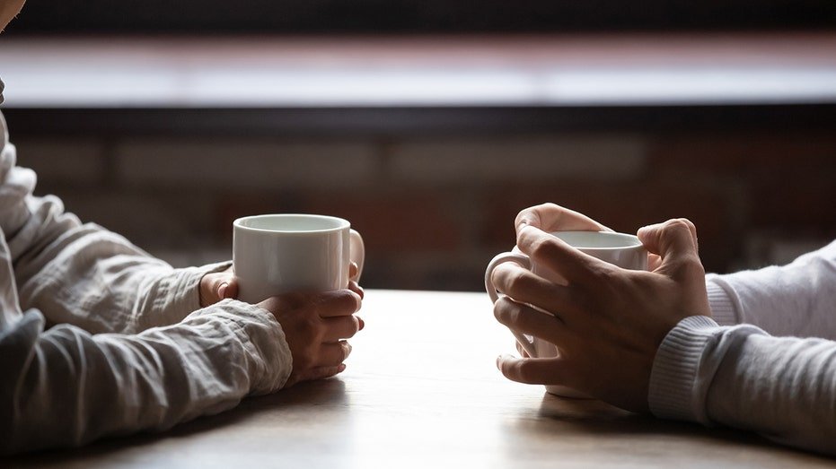 A close woman and a man sitting in a café, carrying warm coffee cups on the table, two young men who spend the weekend in the comfortable cafe together, the concept of romantic history, and visitors drink hot drinks