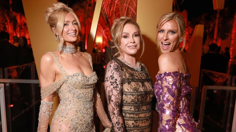 Paris Hilton with her mother and sister pretending to take pictures in different colored dresses