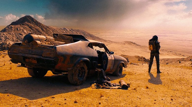 Max looks at the closing horizon while standing in front of his car in 