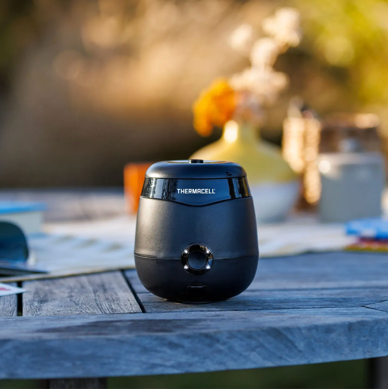 Thermacell Mosquito Repeler, a small semi -circular black unit, sits on a picnic table.