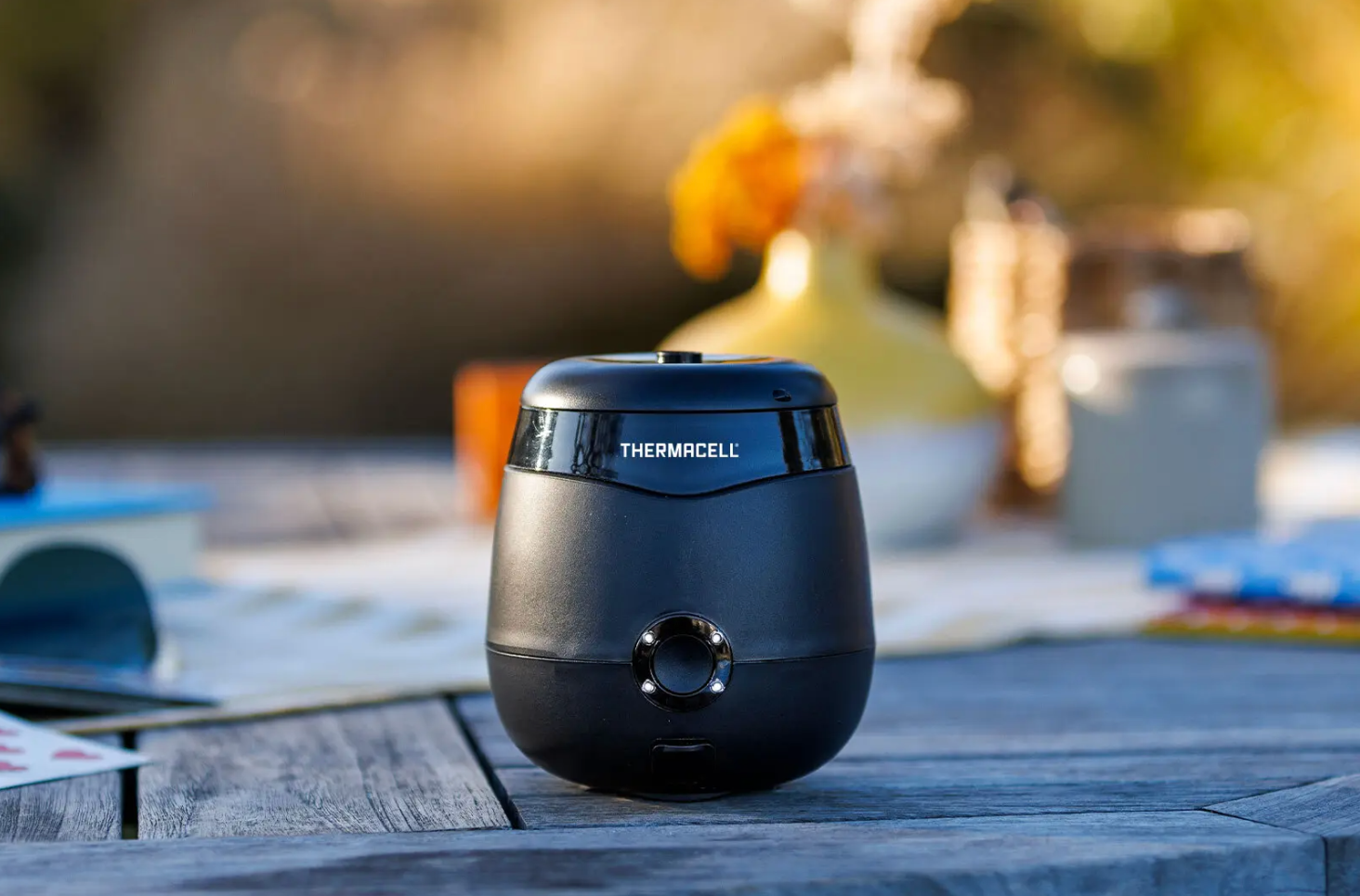 Thermacell Mosquito Repeler, a small semi -circular black unit, sits on a picnic table.