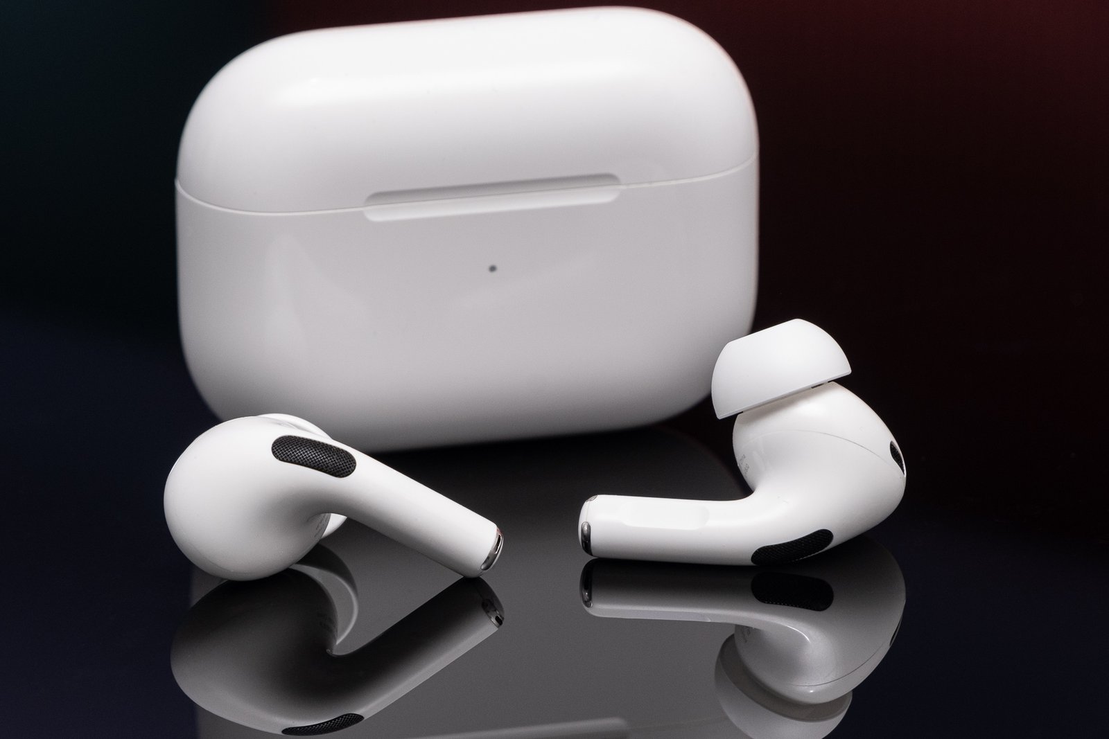 AirPods of the second generation of Apple was photographed on a reflective black surface.