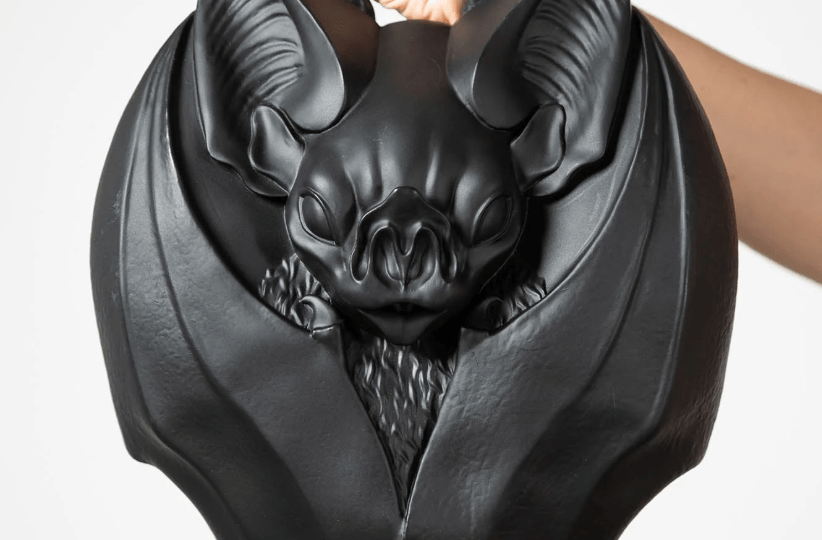 Hand holding handbag in the shape of a bat with its wings folded