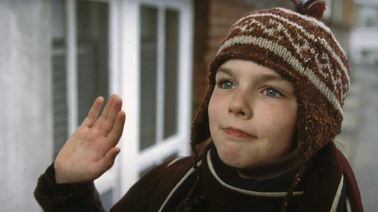 About a boy, Marcus in the winter hat is waving someone