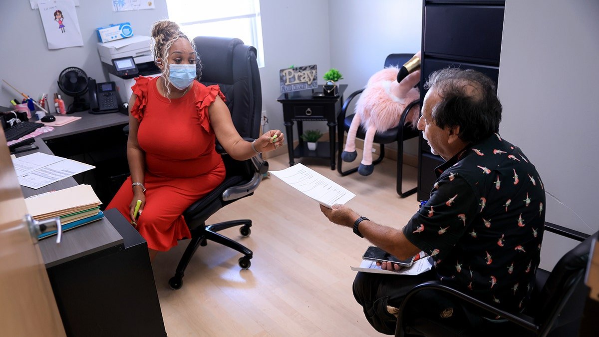Alicia Lester, Director of Status and Service Coordinator, helps Henry Vooff filling medicaid and applying food stamps at the LifeEET4Families Center on May 14, 2025 in Laudergil, Florida.