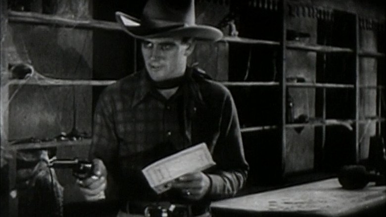 John Wayne in the role of John Masson indicates his pistol in haunted gold
