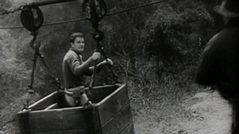 John Wayne in the role of John Masson stands in a haunted gold cage