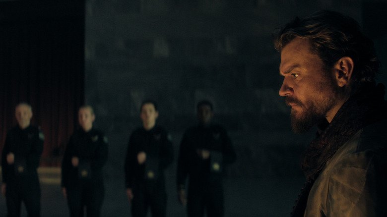 Pilou ASBæK as a muffle stands in front of many servants in the Foundation season 3