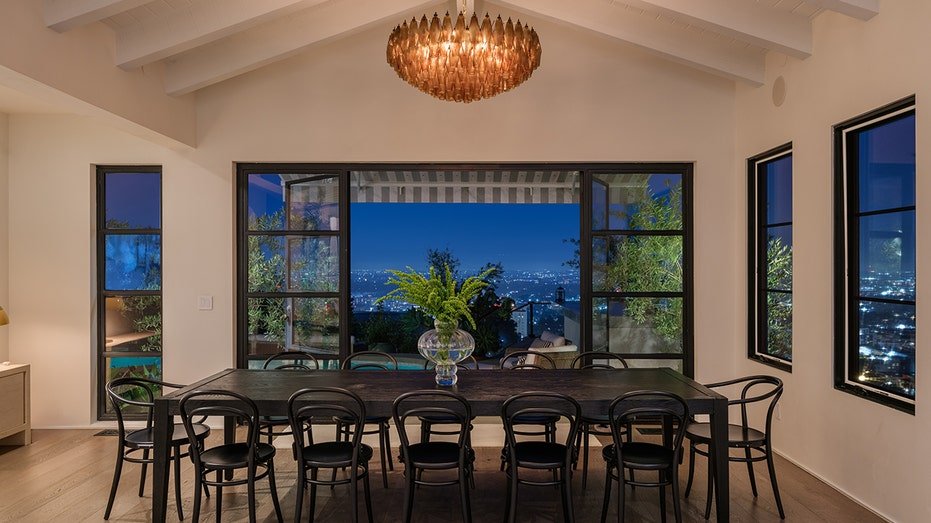 The dining table is in front of the doors leading to the yard, providing views of the city below.