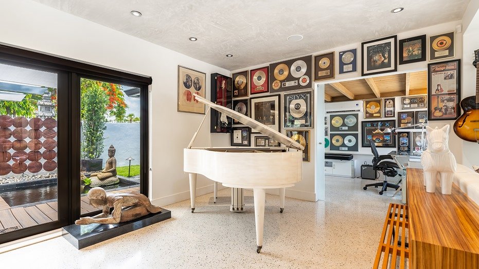 A room with white piano and the records on the wall