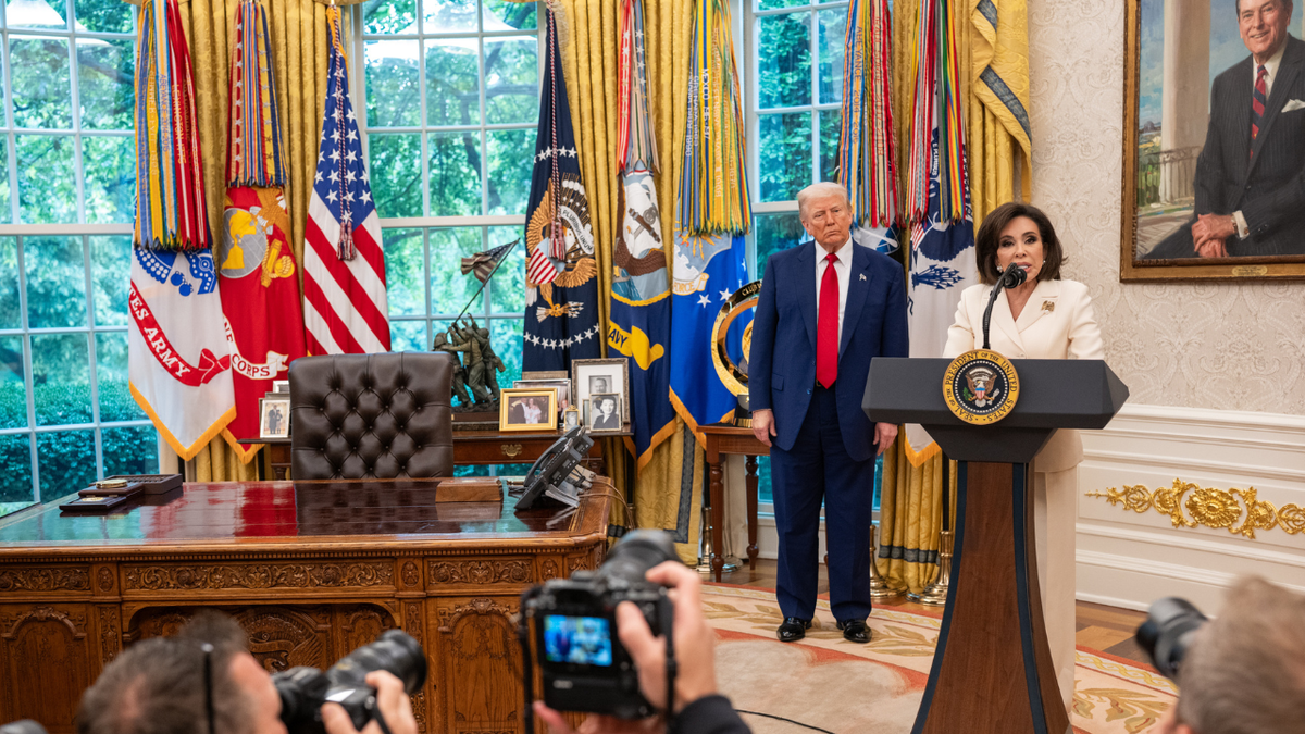 President Trump listens to the notes after a performance ceremony at the Oval Office.