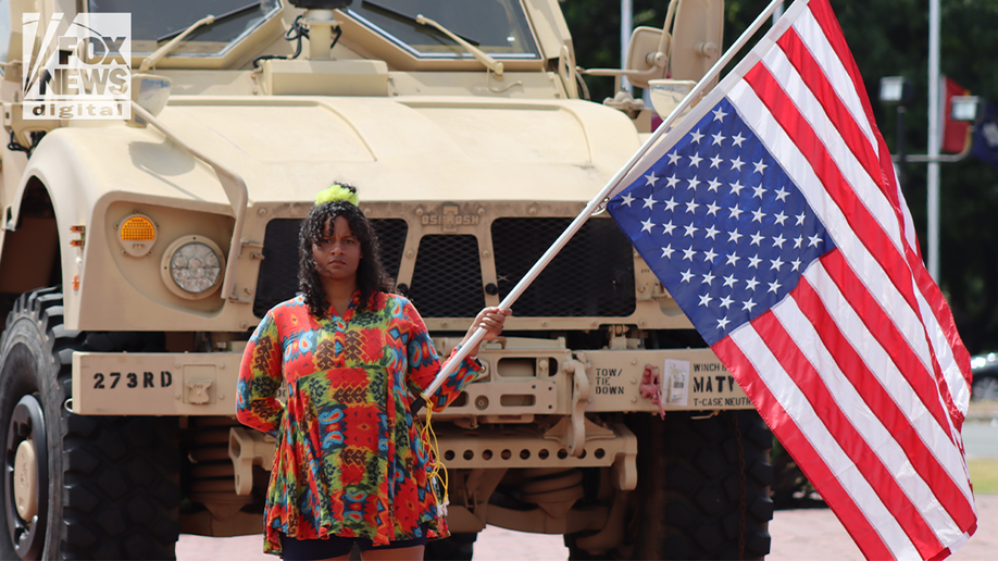A protester with an inverted head in front of the National Guard truck